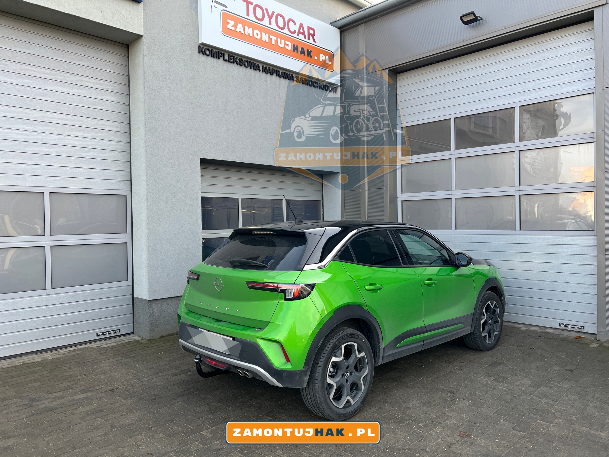 Zdjęcie Opla Mokki z zamontowanym hakiem holowniczym Westfalia A40V, zdjęcie zrobione z prawej strony samochodu, na tle serwisu